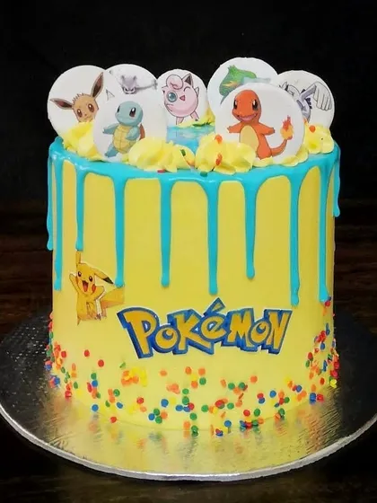 Gotta catch 'em all. This vibrant Pokémon cake is perfect for a kid's birthday party. It features a bright yellow buttercream base, a fun blue drip, and edible prints of favorite characters like Pikachu, Charmander, and Squirtle.