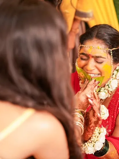 A playful and candid moment during the Haldi ceremony, capturing the bride's infectious laughter.