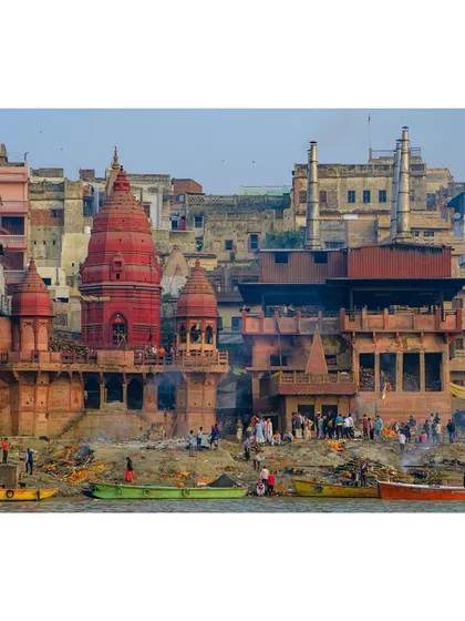 A wide view of Manikarnika Ghat in Varanasi, the primary cremation ghat, showing the constant flow of life and death by the Ganges.