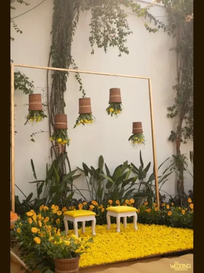 A simple, elegant setup for an intimate Haldi, using a frame, hanging baskets, and a carpet of yellow flowers. This shows that even smaller events can be beautifully designed.