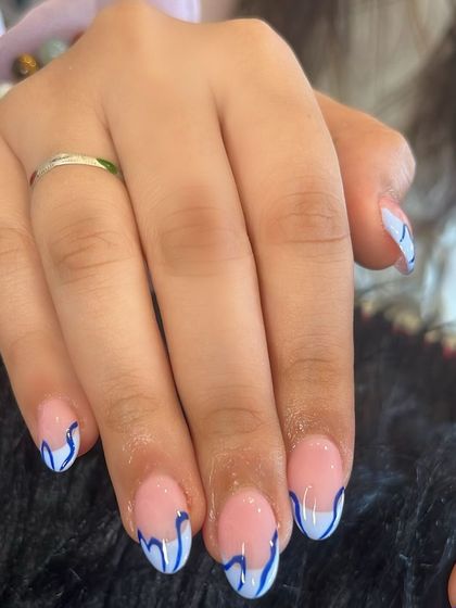 Abstract blue and white French tips on short, natural nails for a pop of artistic flair.
