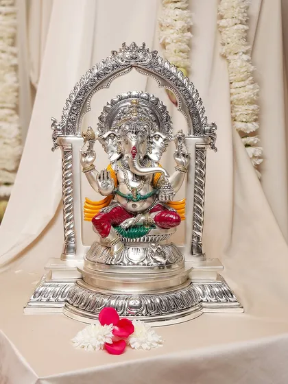 A beautifully crafted silver-plated Ganesha idol, housed within an ornate archway. This piece is perfect for a home temple, bringing a sense of architectural grandeur and divine presence to your worship.