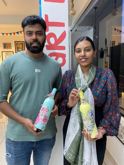A couple with their finished decoupage bottles. It's a fun way to upcycle and create personalized decor for your home.