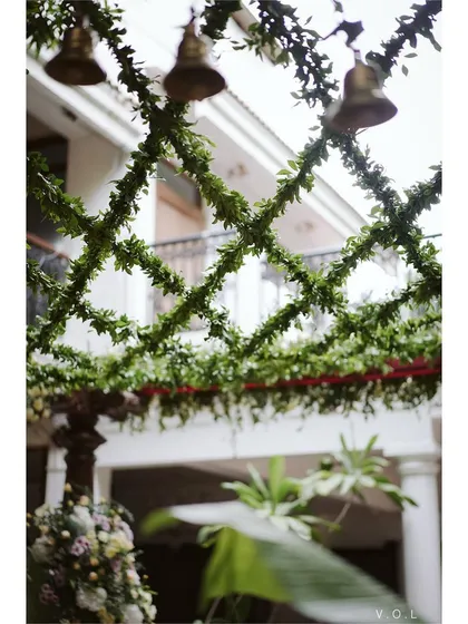 A detail of the garden mandap ceiling, featuring a lattice of greenery and hanging brass bells.