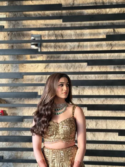 This hairstyle is all about understated elegance, with soft waves that complement the intricate gold lehenga.