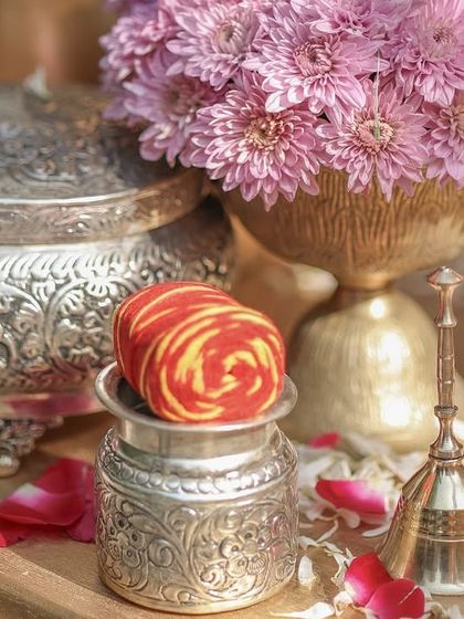 A close-up of traditional silver containers and a 'mauli' thread roll, elements that ground the modern design in sacred ritual.