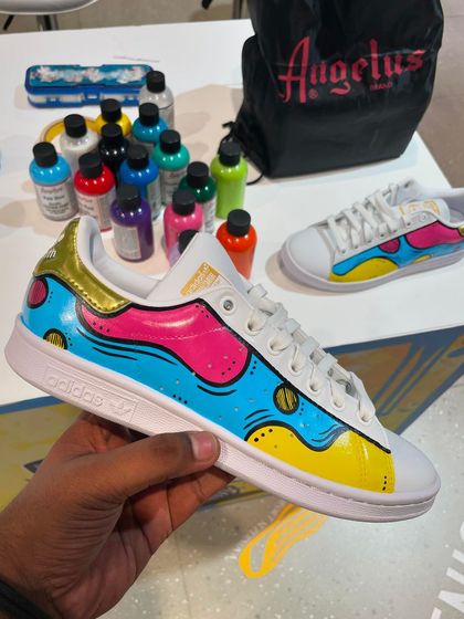 A colorful, pop-art inspired design we painted on a pair of Adidas Stan Smiths during a live event. The bright blue, pink, and yellow create a bold and playful look.