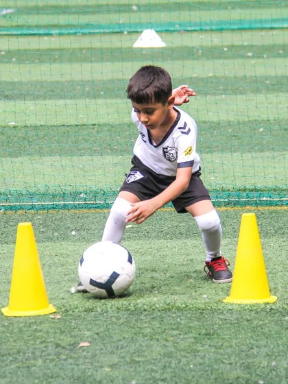 A player demonstrates excellent balance and low center of gravity while dribbling between cones, key attributes for effective ball control.