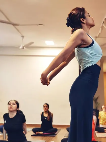 I often demonstrate postures to clarify alignment, as seen here with a chest-opening stretch. My goal is to make the practice accessible and understandable for everyone.