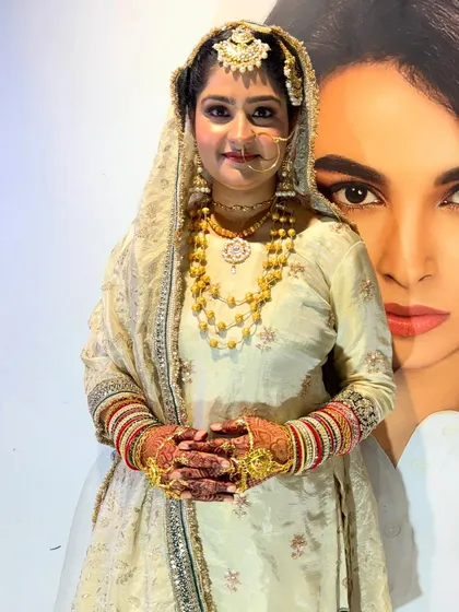 This full-length view shows how our bridal makeup translates from a close-up to the entire look. The makeup remains impactful and polished, tying together her entire bridal outfit, from the maang tikka to her henna-adorned hands.