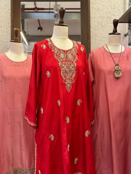 A detailed shot of a red silk kurta with paisley-shaped silver embroidery, a classic and timeless design.