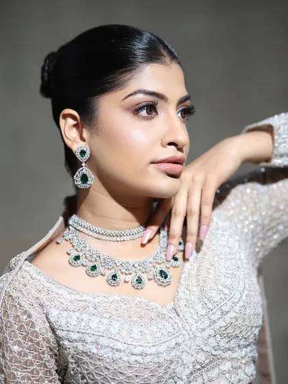 A beautiful portrait showcasing the elegance of this emerald and zircon layered necklace. The model's pose highlights the intricate design and sparkle of the piece, perfect for a reception.