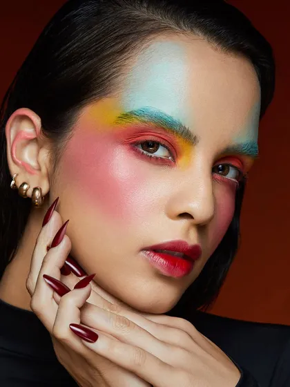A creative and colorful look with a rainbow of pigments blended across the forehead and cheeks, celebrating the joy of color.
