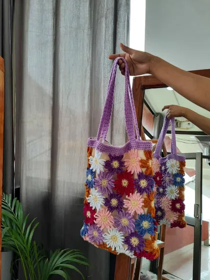 Another angle of the multi-color daisy tote bag, focusing on the intricate details of the individual flowers. Each daisy is crocheted with different colored petals, making every bag a unique piece of wearable art.