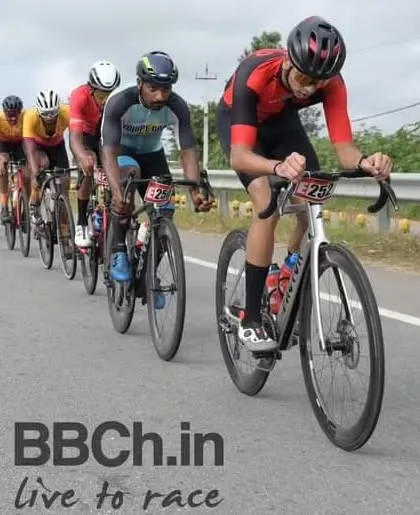 The elite peloton, led by a rider from The Bike Affair, maintains a high pace on the open road.