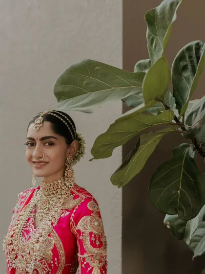 A lovely portrait of the bride, her smile framed by a fiddle-leaf fig plant. The touch of green adds a fresh, modern feel to this classic bridal shot.