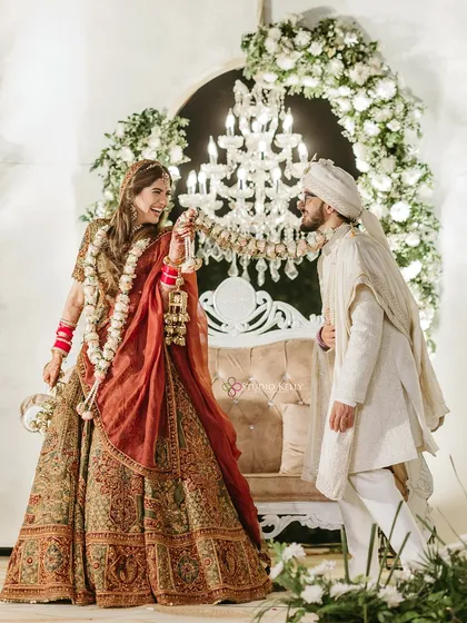 A playful Varmala moment, with the groom leaning in to get the garland, capturing the fun of the ceremony.
