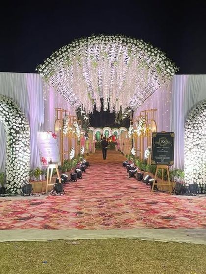 A dreamy floral entrance for an outdoor wedding. We created multiple arches covered in white flowers leading into a tunnel with a ceiling of hanging wisteria, making for a magical walk-in experience.