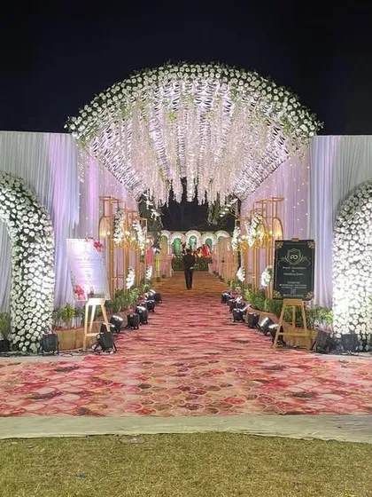 A dreamy floral entrance for an outdoor wedding. We created multiple arches covered in white flowers leading into a tunnel with a ceiling of hanging wisteria, making for a magical walk-in experience.