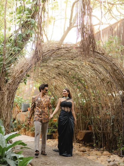 A stylish couple holds hands as they walk through a beautifully decorated garden path for their cocktail party. A perfect blend of nature and glamour.