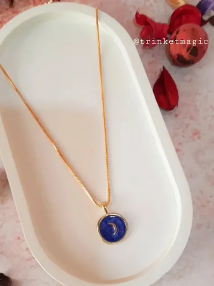 This beautiful necklace features a deep blue enamel pendant with a crescent moon, perfect for adding a touch of nighttime magic to your look.