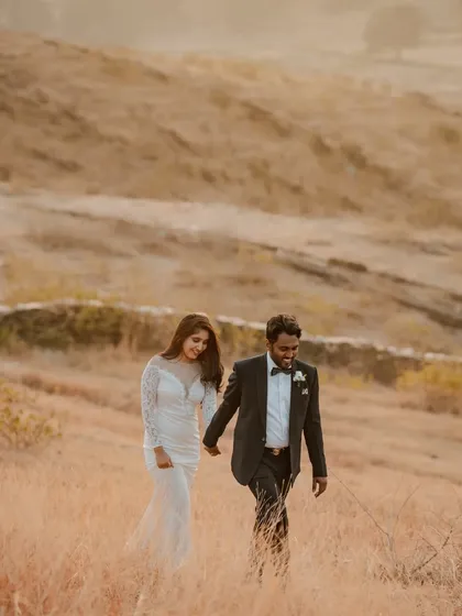 Rishab and Kratika walk hand-in-hand through the golden fields of Udaipur during their pre-wedding shoot. The formal attire against the rustic landscape creates a beautiful, romantic contrast.