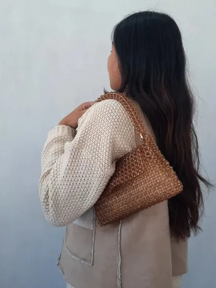 This photo shows how the metallic bronze beaded bag looks when carried over the shoulder. The light catches the beads, giving the bag a beautiful shimmer. It's a versatile piece that works well for both day and night.