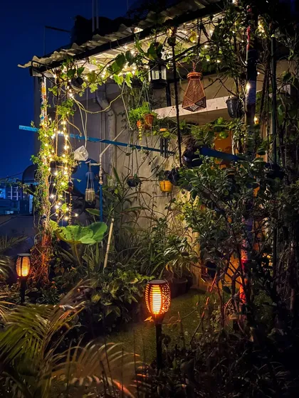 A duplicate image that emphasizes the lush, vibrant feel of the garden post-rain, with the solar torches adding a fiery contrast to the cool night air.