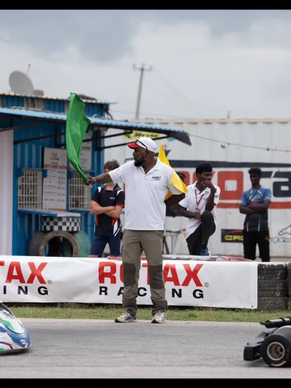An official waves the green flag to start a race, with our team watching from the sidelines.
