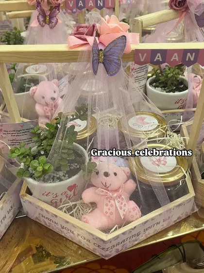 A detailed shot of the butterfly-themed hamper for baby Vaani. The personalized banner, custom planter, and adorable pink bear candle come together beautifully.