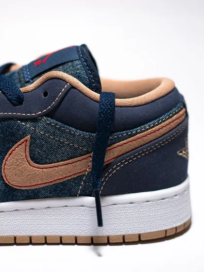 A side profile close-up of the Jordan 1 Low 'Denim', highlighting the tan suede swoosh against the dark blue denim.