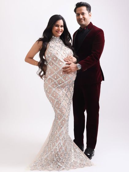 A classic, full-length portrait of the glamorous couple. The expectant mother radiates confidence and joy in her embellished gown.
