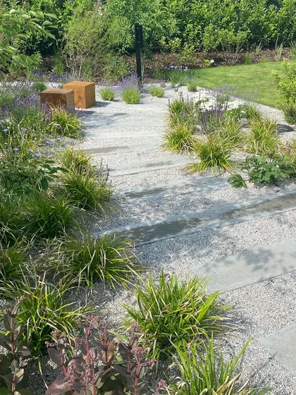 A gravel garden with stepping stones and drought-tolerant plants. This style of xeriscaping is a sustainable and low-maintenance option that we offer for modern homes.