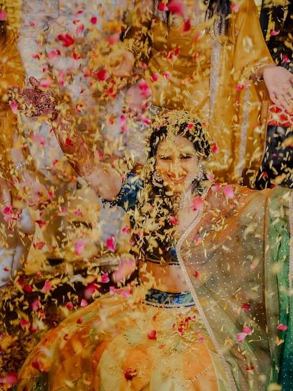 An artistic shot of the bride being showered with a storm of colorful petals during her Haldi.
