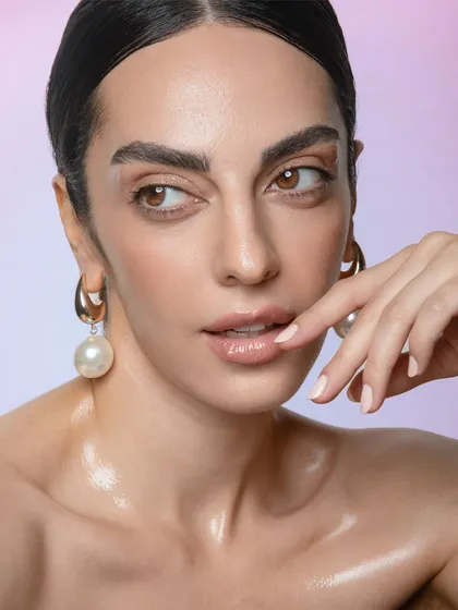 A chic and contemplative pose. The makeup is all about a healthy sheen, with a neutral lip and defined brows creating a sophisticated and modern beauty look.