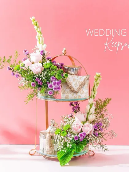 Treasured wedding keepsakes. This two-tiered stand is perfect for displaying smaller gifts or favors, decorated with fresh flowers in shades of pink and purple.