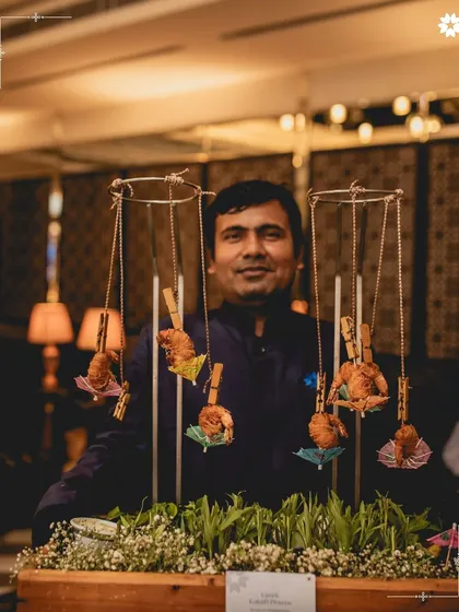 An innovative way to serve pass around appetisers. Here, crispy fried prawns are clipped to a hanging mobile, creating an interactive and whimsical presentation that delights guests.