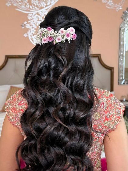 The full back view of the floral half-up style, with soft waves cascading down.