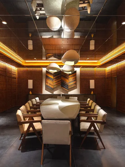 The dramatic basement dining room of the Bammi Residence, as featured in Living Etc. India. The mirrored ceiling and custom lighting create an expansive, atmospheric setting.