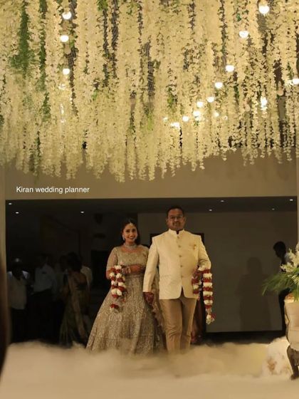 A couple making their grand entrance through a cloud of fog, with a ceiling of hanging white flowers above them. This creates a truly magical and theatrical moment.