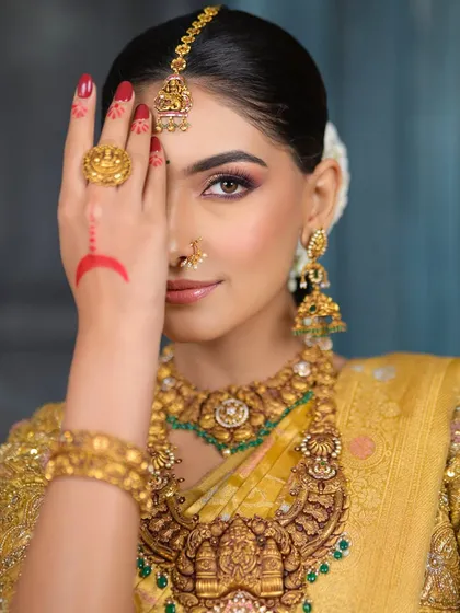 A creative half-face shot, highlighting the beautiful eye makeup and the traditional red design on her hand.