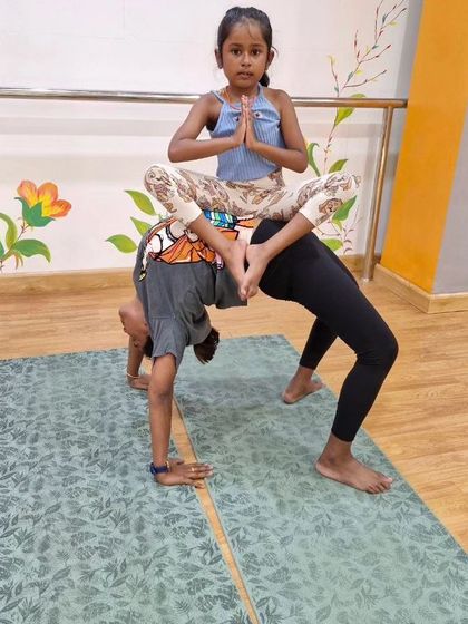 A beautiful moment of family yoga, where a child finds her balance and focus supported by her family members. It's a pose that builds strength and connection across generations.