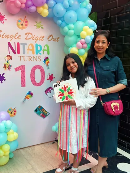 Celebrating a special 10th birthday. The birthday girl proudly displays the beautiful mandala canvas she created, a perfect memory from her unique art-themed party.