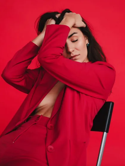 A powerful and emotive pose against a solid red background. This portrait is all about conveying strength and passion through body language.