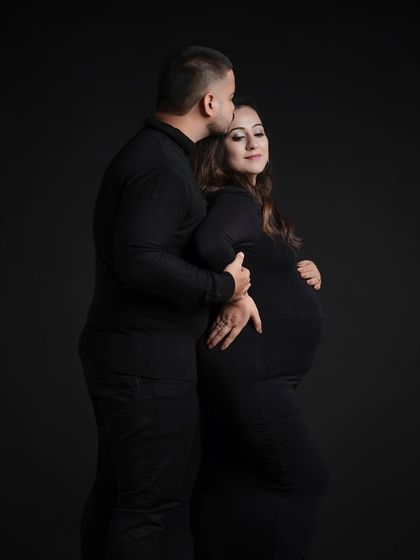 A timeless pose against a black backdrop, with the partner's gentle kiss conveying love and tenderness.