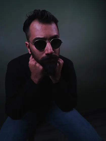 A pensive, low-key portrait. The deep shadows and focused lighting create a timeless feel, suitable for dramatic headshots or editorial fashion spreads.