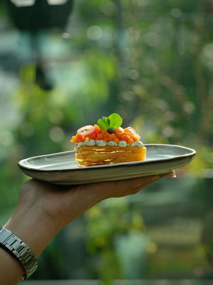 A delicate salmon tartlet, held up to showcase its intricate layers, created for a special tasting menu.