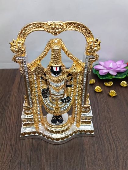 A grand terracotta idol of Lord Venkateshwara, intricately decorated in black and gold, standing within a beautiful arch.