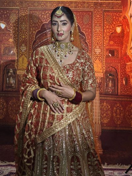 A model showcasing a red and gold sequined lehenga against a traditional Rajasthani backdrop. This outfit is perfect for shoots or for a bride's big day.
