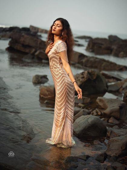 A standing pose on the rocks, with the sequined gown shimmering in the evening light. This is a perfect example of a high-fashion editorial shoot in a natural location.